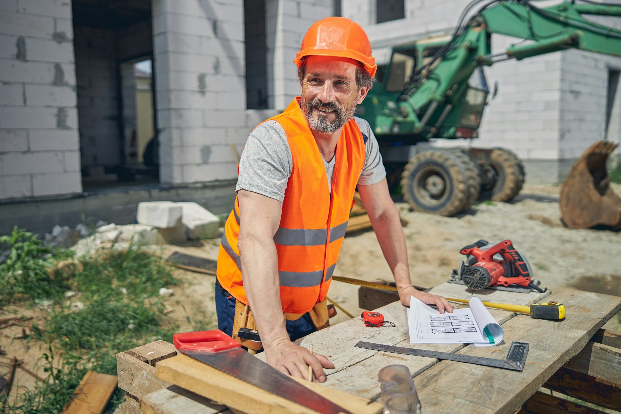 Construction professional reviewing plans on-site, with costs and invoices managed through Rounded.