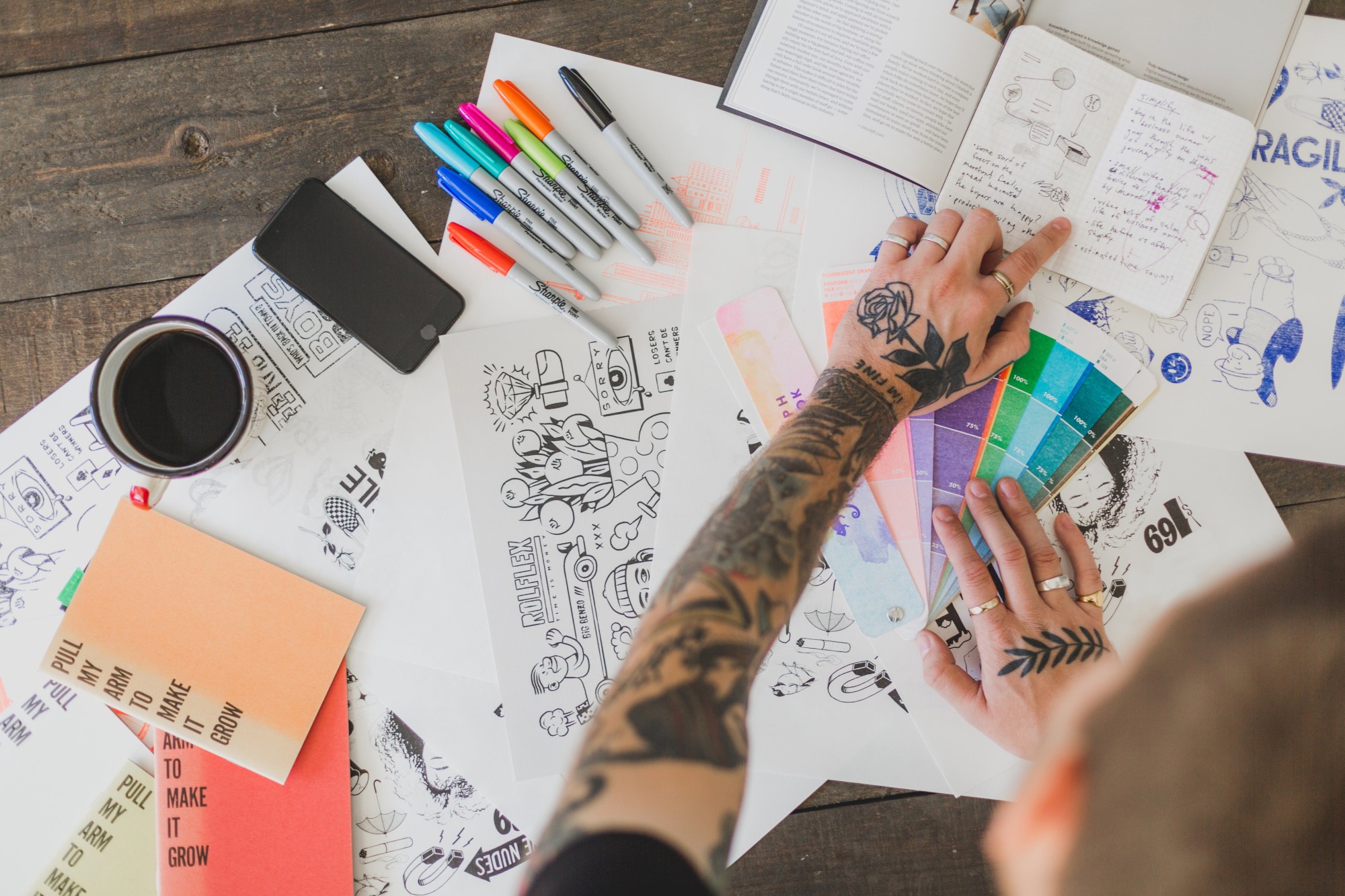 Designer planning creative projects with notes and sketches, supported by Rounded for expenses and invoices.